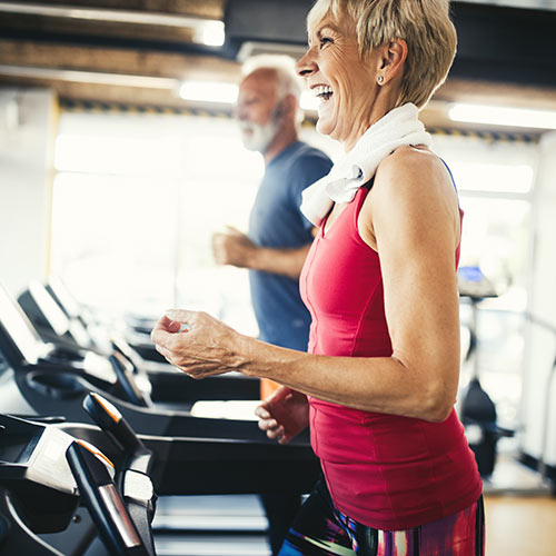 Older woman and man running on treadmills